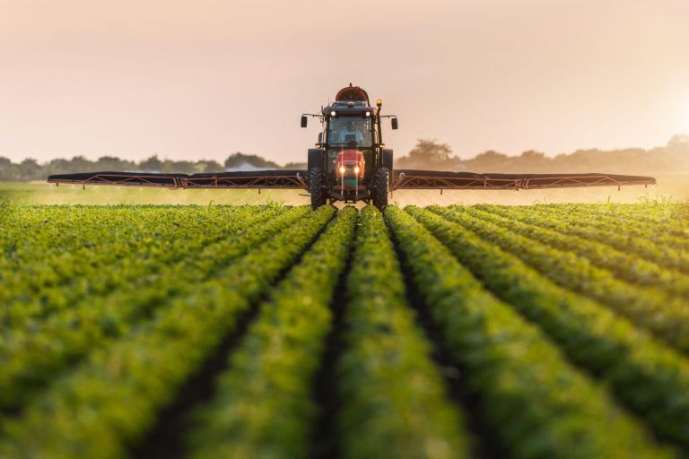 Tractor spraying pesticides on soybean field  with sprayer at spring