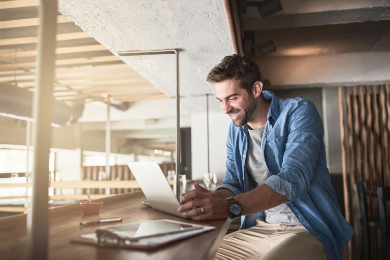 Man in cafe, laptop and small business owner, entrepreneur in hospitality industry and connectivity. Happy male professional, coffee shop franchise and wireless connection with digital admin on pc.