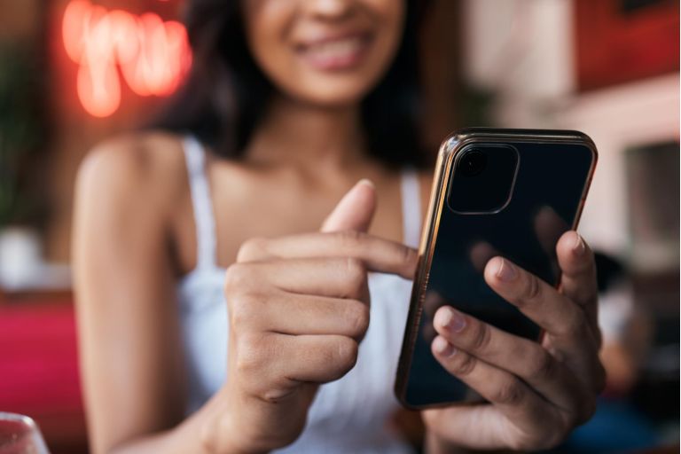 Restaurant, bar and smartphone in hands of woman for social networking, mobile chat app and internet scroll, surfing or search. Cafe, young customer and using phone for social media post or an update.