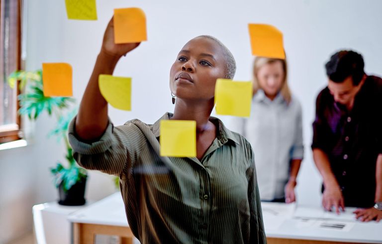 Black woman, glass wall and sticky note for planning business, startup strategy and meeting reminder in office. African lady, moodboard and notes for project, brainstorming and franchise development.