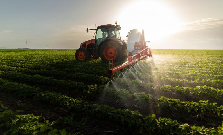 Tractor spraying pesticides on soy field  with sprayer at spring