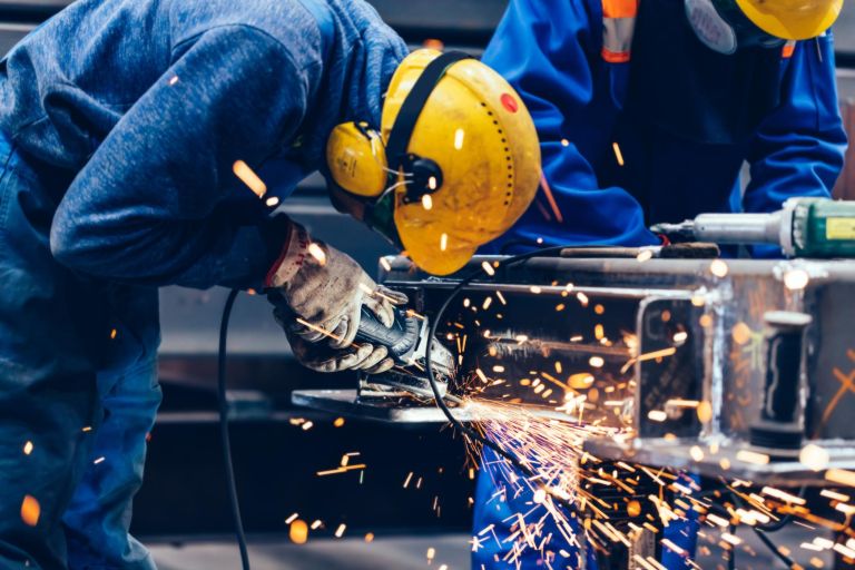 Worker grinding in a workshop. Heavy industry factory, metalwork