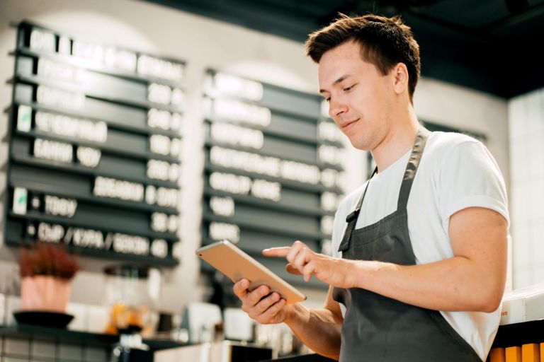 Sells drinks and food in cafes. An employee counts finances in an online table. An entrepreneur and his restaurant are a small business. A man works in a cafe on a laptop.