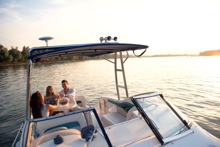 Young attractive people having good time on a boat with drinks