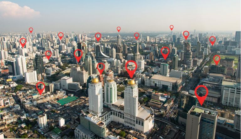 Searching location on map and pin above blue tone city scape and network connection, internet of things, satellite navigation system concept