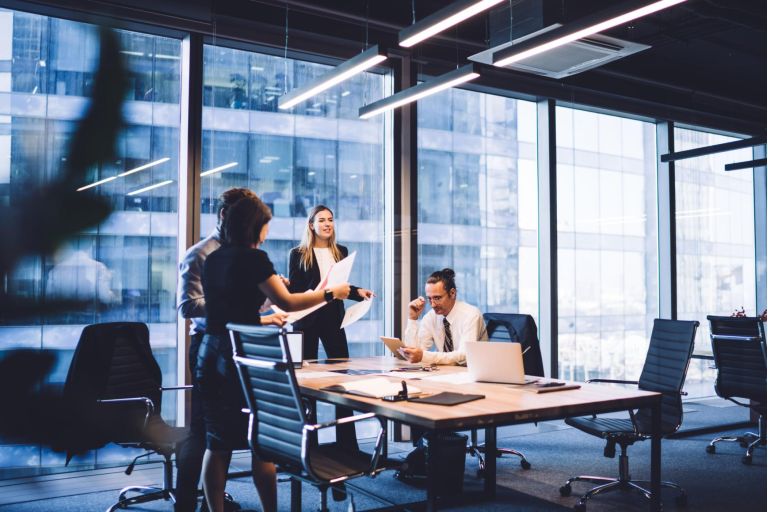Cooperation process of professional male and female partners, successful corporate colleagues analyzing information from paper documents during working time in conference room with desktop